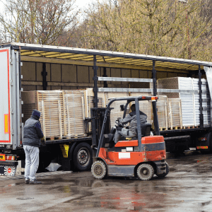 Manned forklift truck unloading pallets from a heavy goods vehicle